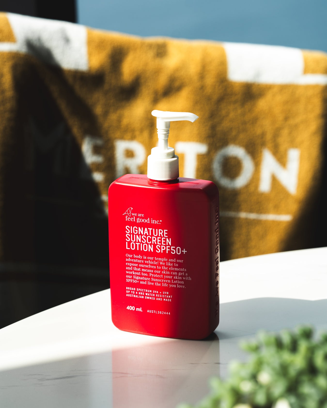 Red SPF50+ sunscreen lotion bottle ready for long summer days at the beach, a key summer essential for sun protection.