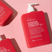 Five red bottles of WAFGI sunscreen and lotion products arranged diagonally on a solid pink background.