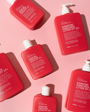 Five red bottles of Bad Ass Brand Inc. sunscreen and lotion products arranged diagonally on a solid pink background. Shop Meriton Suites. We are feel good inc. spf sunscreen.
