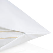 Close-up of a white pillow with a gold zipper on a white background.  The Lad Collective bed linen from Shop Meriton Suites.