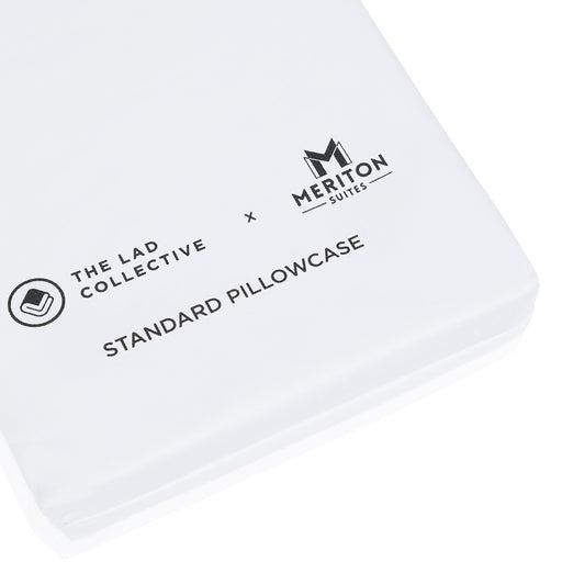 White pillowcase with 'Meriton Suites' and 'The Lad Collective' branding on a white background