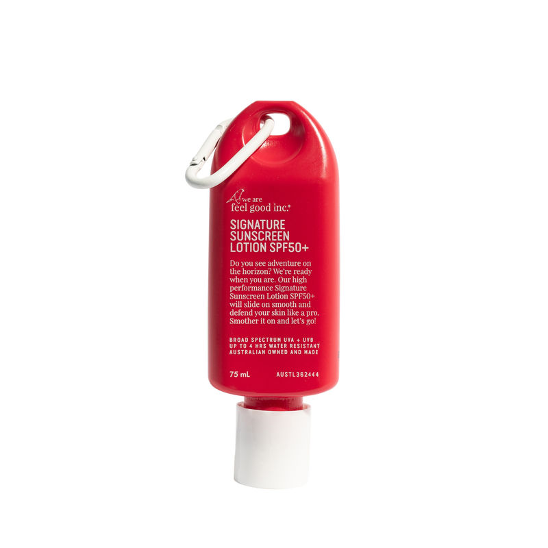 A red squeeze tube of feel good inc. Signature Sunscreen Lotion SPF 50+ with a white cap and a white carabiner clip, shown on a plain white background. Shop Meriton Suites. We are feel good inc. spf sunscreen.